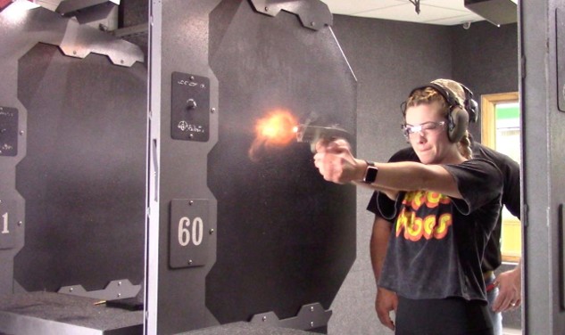 Shooter practicing with a handgun at indoor range with proper safety gear